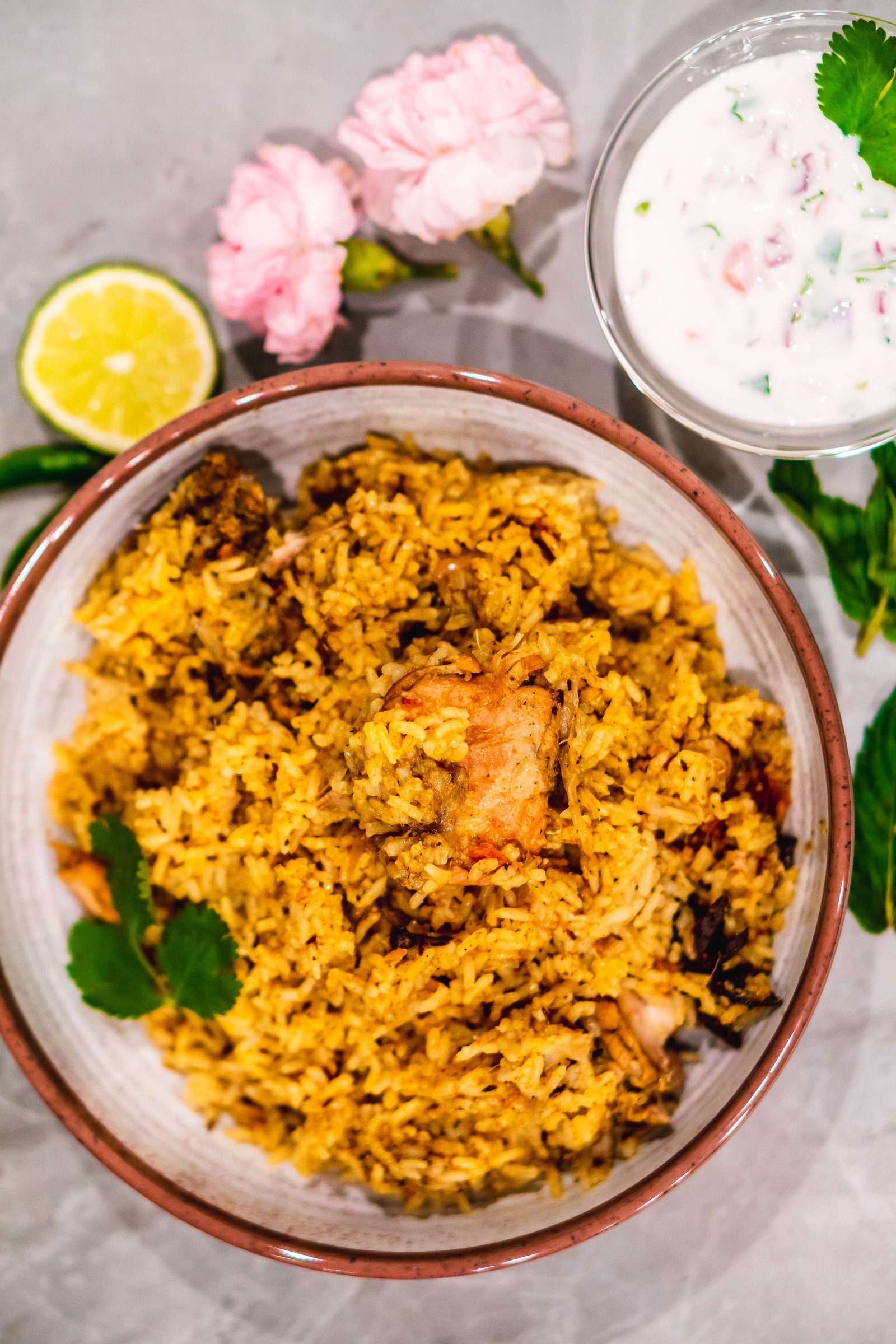 Overhead view of biriyani served with yogurt and lemon garnish