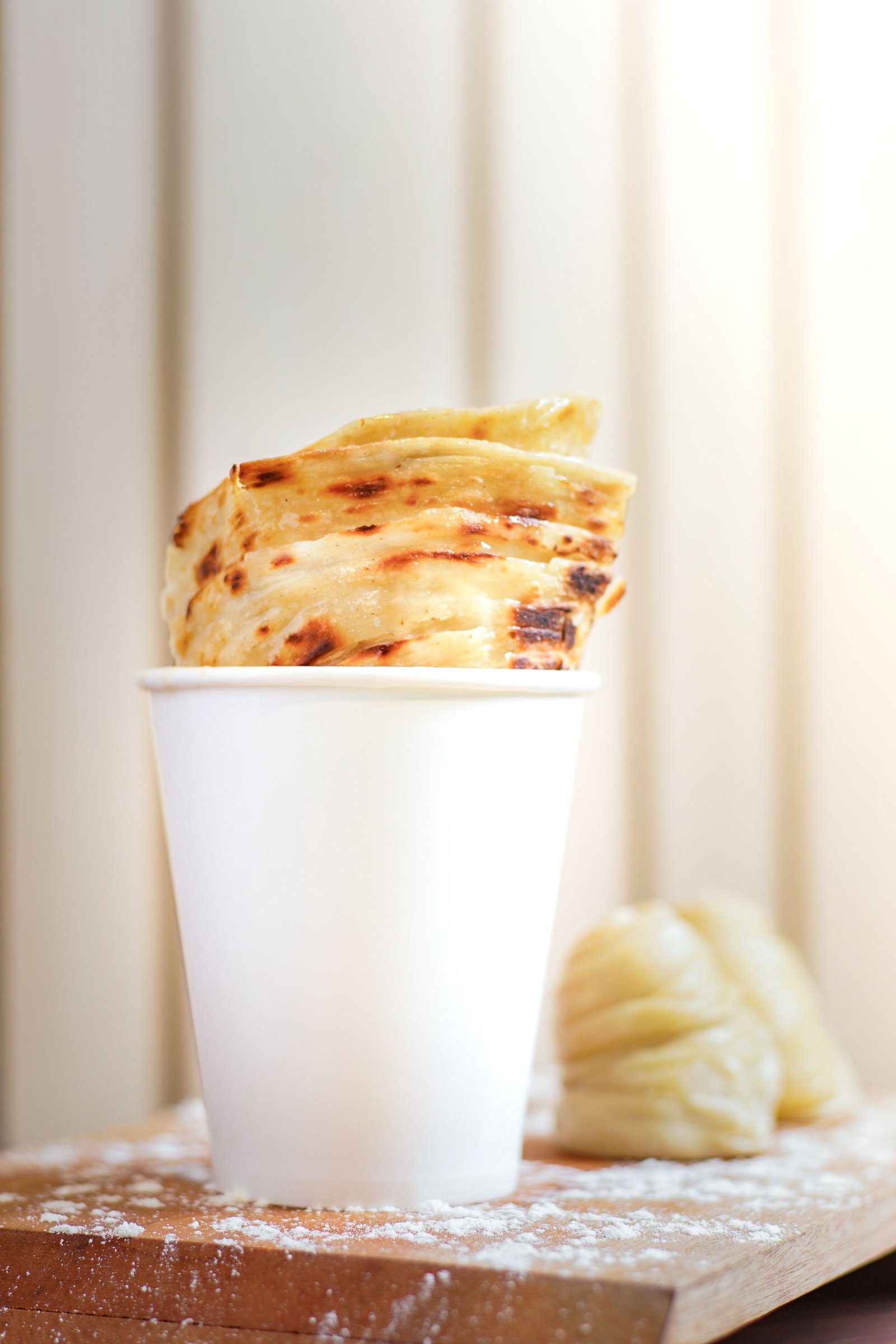 Flaky parotta served in a paper cup